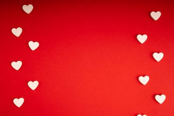 Top view of white wooden hearts on the red paper background. Flat lay for Valentine's Day. Concept of love....