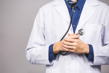 Handsome young medic doctor holding a stethoscope, isolated over grey background.