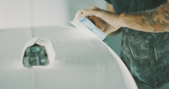 Surfboard shaper shaping a new surfboard with skill and precision, craftsman working with his hands
