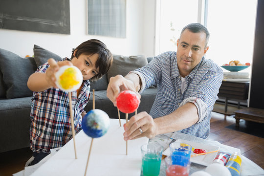 Father and son preparing solar system model at home