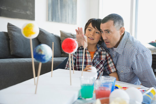 Father explaining solar system model to son at home