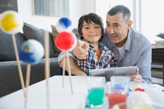 Father and son studying solar system model at home