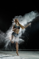 Fototapeta na wymiar Beautiful girl model on a black background throws flour