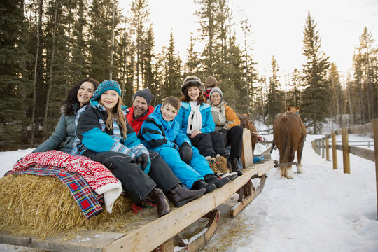 Portrait Of Family Riding On Horse-drawn Sleigh In Snow