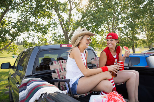 Women relaxing in truck bed at tailgate barbecue