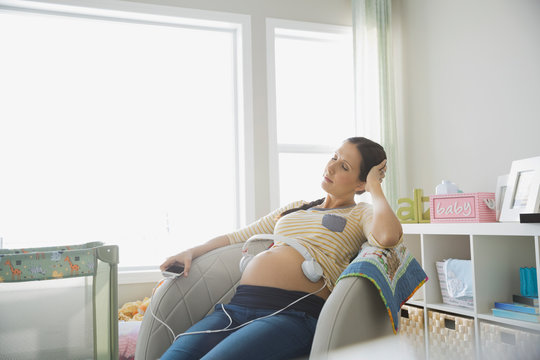 Relaxed pregnant woman with headphones on her belly