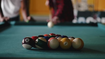 The billiard balls are colorful. The table is green. People play billiard.