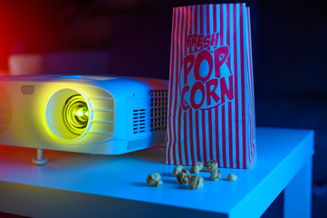 Watching movies with popcorn. Projector and creative light. Concept of cinema