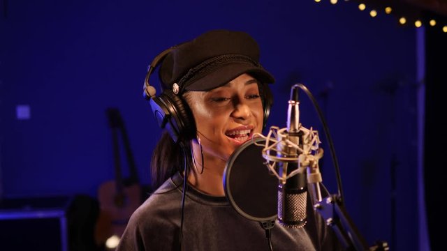 Female Singer / Popstar recording an Album in the studio - She sings into the Microphone with headphones on