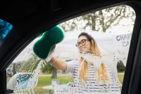 Woman washing car window at charity car wash