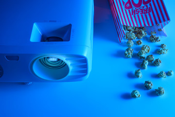 Watching movies with popcorn. Projector and creative light. Concept of cinema