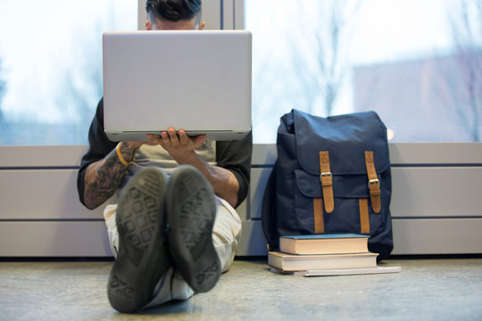 College student using laptop on floor