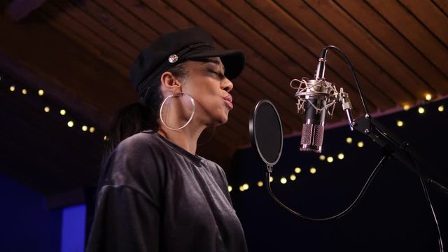4K: Female Singer / Popstar recording an Album in the studio - She sings into the Microphone. Vocalist singing a song. Looking up