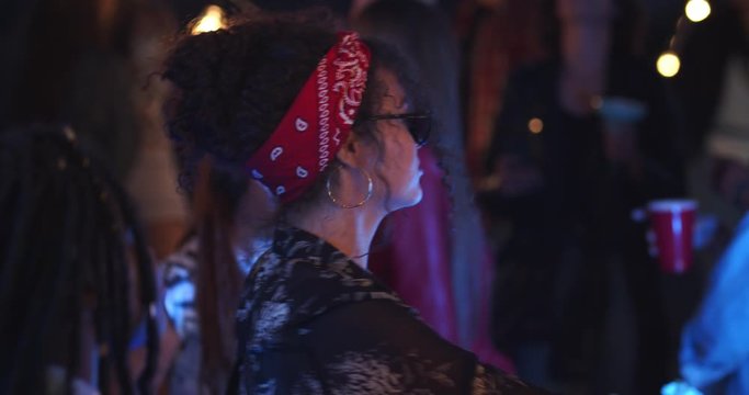 Caucasian young pretty girl dancing alone in the rhythm of music at the party in the crowd. At night. Outdoor. Close up.
