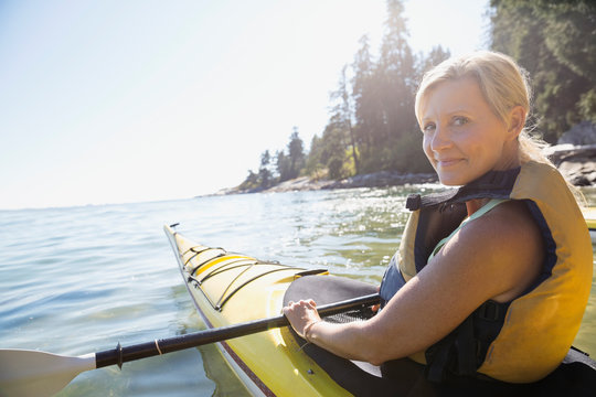 Portrait of woman kayaking on sunny ocean
