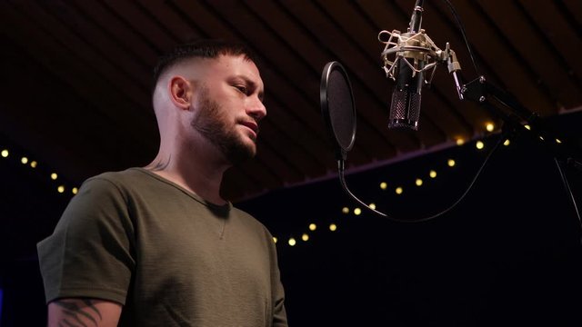 Male Singer / Popstar recording an Album in the studio - He sings into the Microphone & Popshield&nbsp;. Low