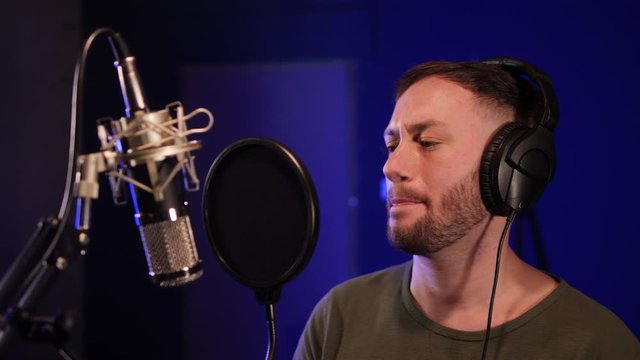 Male Singer / Popstar recording an Album in the studio - He sings into Microphone with headphones on