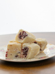 Delicious white fudge with cranberries on a plate with a white background