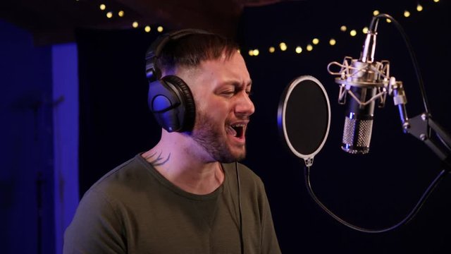 Male Singer / Popstar recording an Album in the studio - Singing into the Microphone with headphones on