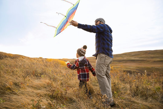 Father and son with kite walking in field