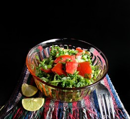 Nutritious watercress salad with tomato on black background. Vegan food