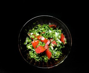 Nutritious watercress salad with tomato on black background. vegan food