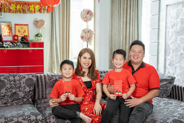 Asian family with two son holding ang pao smiling looking at camera.Asian Chinese family celebrates...