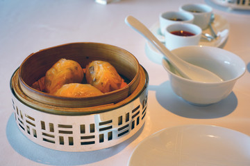 Dish of steamed Chinese dim sum dumplings in a silver and bamboo steamer basket