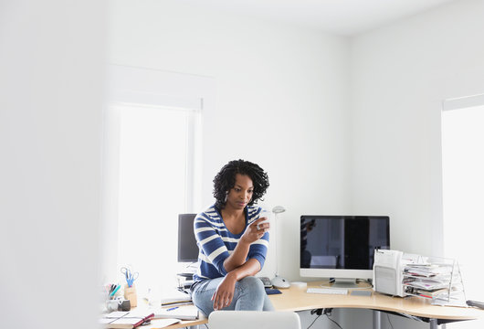 Woman using mobile phone in home office