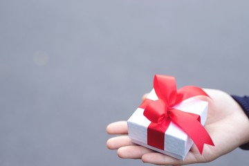 Red bow gift box in woman's hand for lover on birthday, new year, valentines day