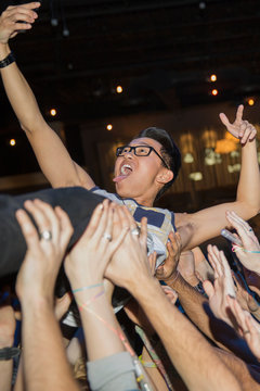 Enthusiastic man taking selfie while crowdsurfing at concert
