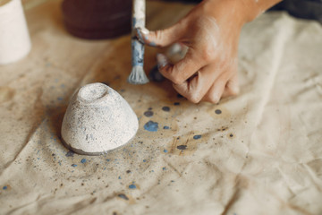 Woman in a pottery. Master make a dishes. Artist works with a clay