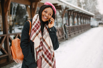 Fototapeta premium Cute black woman have fun in a city. Beautiful black girl in a pink beret.