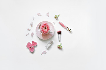 Styled feminine flat lay on white background, top view. Romantic still life - cup of tea, rose petals, perfume, makeup brush and candle in the shape of a heart. Time for morning tea