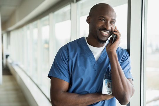 Smiling surgeon talking on cell phone at window