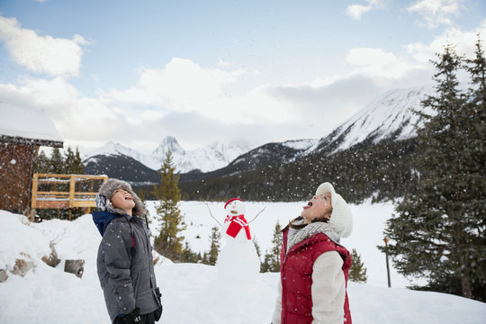 Boy and girl tasting snow below mountains