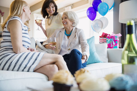 Women drinking wine at party in living room