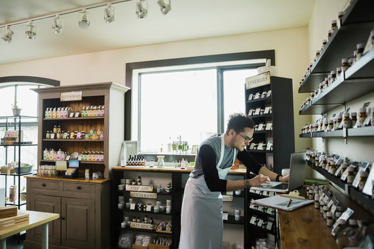 Apothecary shop owner working at laptop
