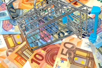 inverted empty shopping cart on the background of euro banknotes. concept of high cost food basket or purchasing power