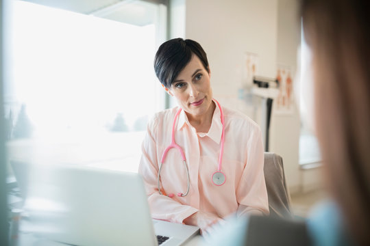 Doctor Listening To Patient In Clinic Office