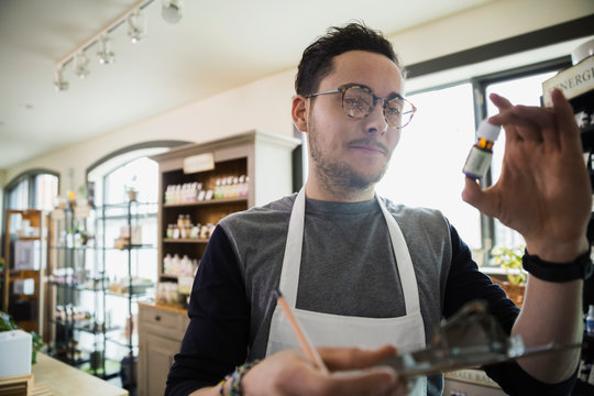 Apothecary shop owner examining essential oil bottle