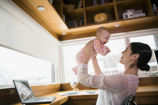 Mother holding baby in home office