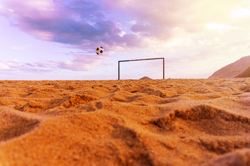 Soccer Ball In Air To Score Goal On Sandy Ocean Beach At Sunset