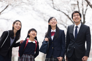 桜並木の下を歩く家族
