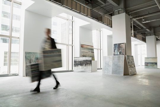 Art dealer walking with paintings in art gallery