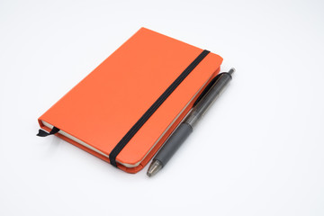 Orange notebook with pen on white background