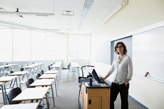 Portrait Smiling Professor Preparing At Computer In Classroom