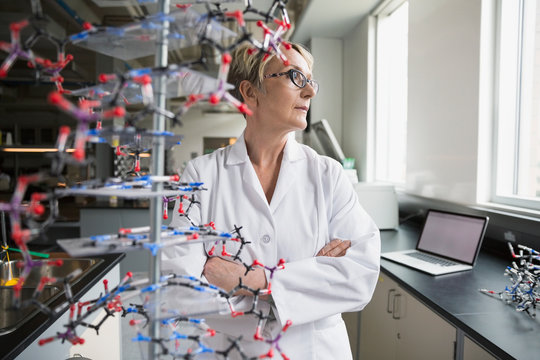 Pensive scientist behind molecule model in laboratory