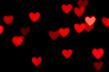 Black background with bright red warm heart shaped bokeh lights. Holiday, Valentines Day background. Ideal to layer with any design. Horizontal