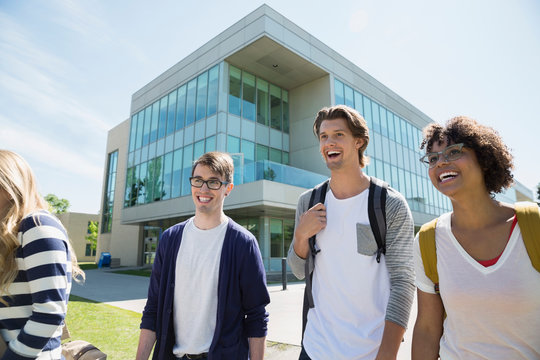 Smiling college students walking on sunny campus